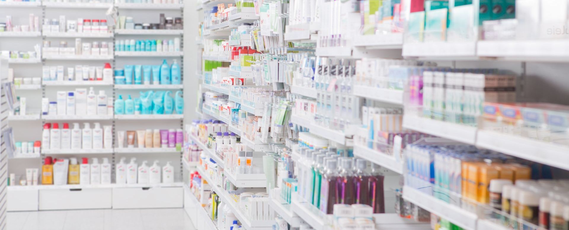 A blurred image of a pharmacy filled with lots of products on shelves.