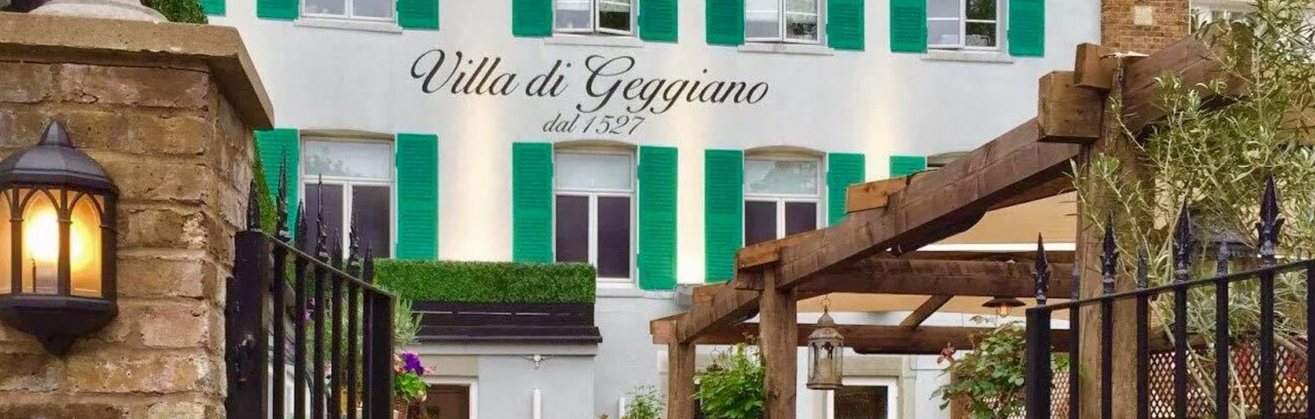 A white building with green shutters and a sign that says villa di giorgione
