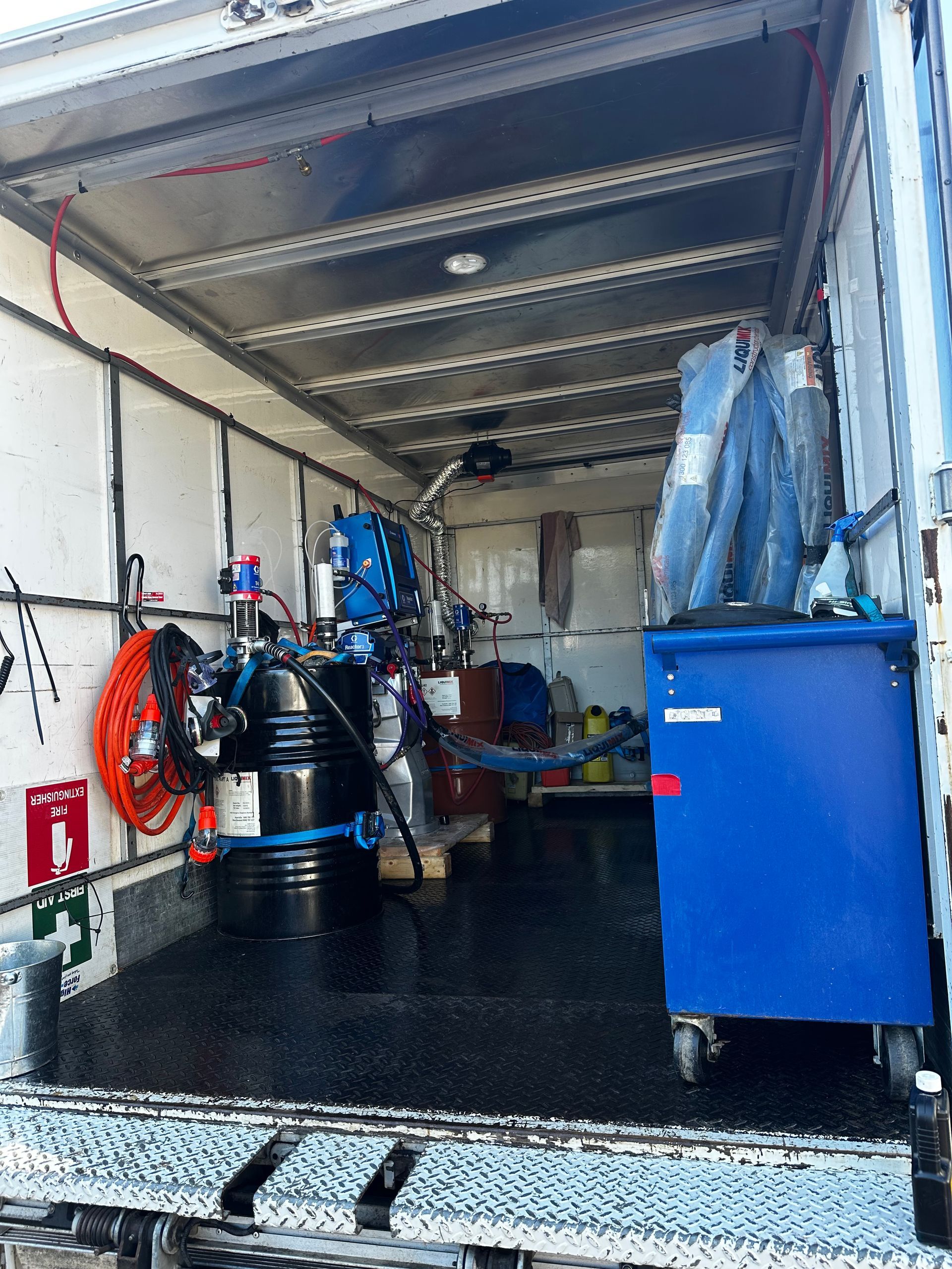 Interior of a service truck with equipment. Black drums, blue cabinets, hoses, and tools are visible — Proshield Insulation & Waterproofing In Shell Cove, NSW