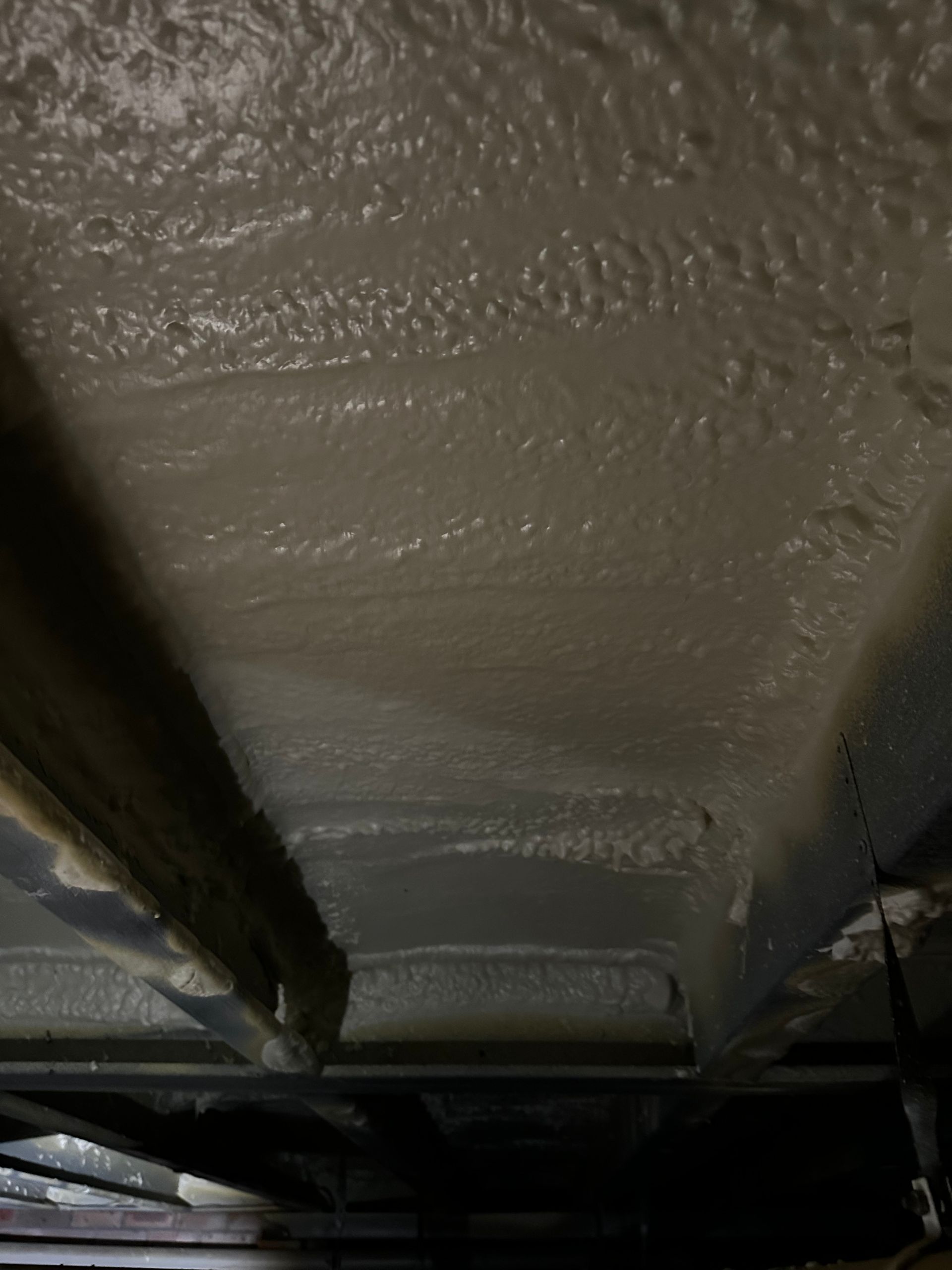 Spray foam insulation on the underside of a floor, viewed from below; light gray color — Proshield Insulation & Waterproofing In Shell Cove, NSW