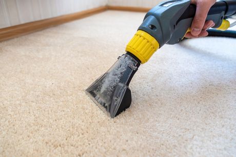 A person is cleaning a carpet with a vacuum cleaner. — Durant, OK — James Dry Carpet & Upholstery Cleaning Service