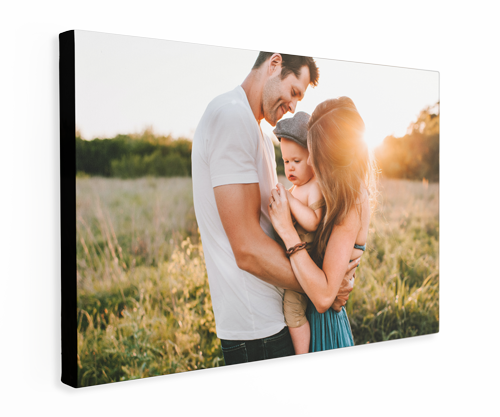Family embraces in field with sunlit background. Man, woman, and baby.
