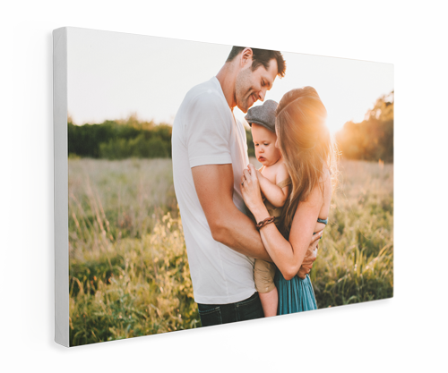 Family embracing outdoors in sunlight. A father, mother, and baby are close, smiling.