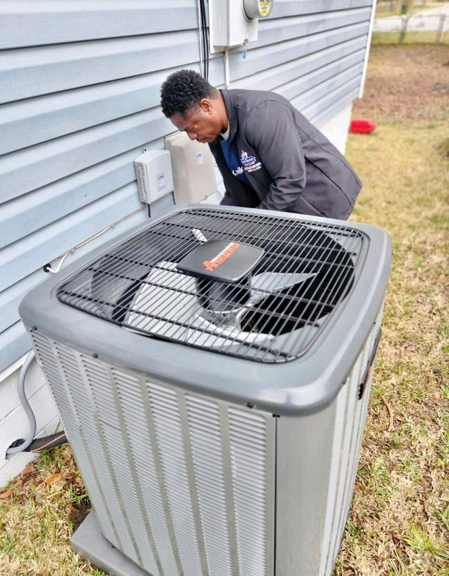 Technician inspecting an outdoor air conditioning unit beside a house.