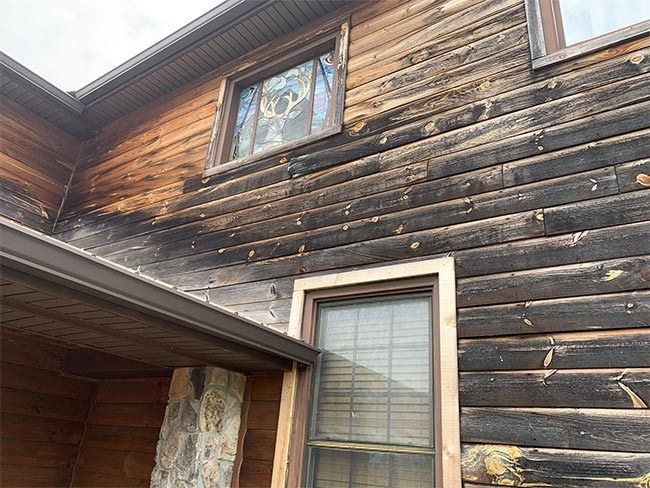 Charred wooden house exterior with a window and small overhang beneath a roofline