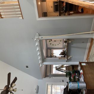 Living room with high ceiling, ceiling fan, staircase, and view into adjacent kitchen and dining area.