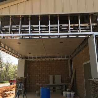 Unfinished garage interior with exposed framing, cinder block wall, ladder, blue barrel, and construction materials