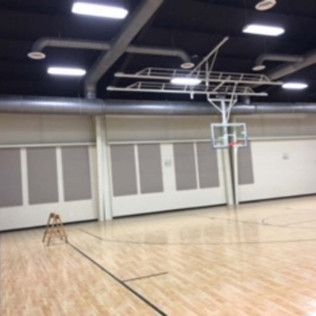 Empty indoor basketball court with polished wood floor and overhead lights