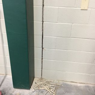 Green padded column beside a cinderblock wall, with exposed cables scattered on the floor.