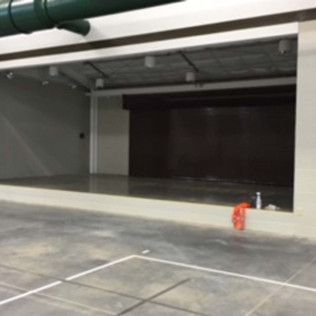 Empty parking garage interior with concrete floor and a red cone near the entrance