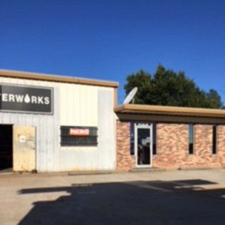 Low brick and metal storefront under a clear blue sky with a paved parking lot