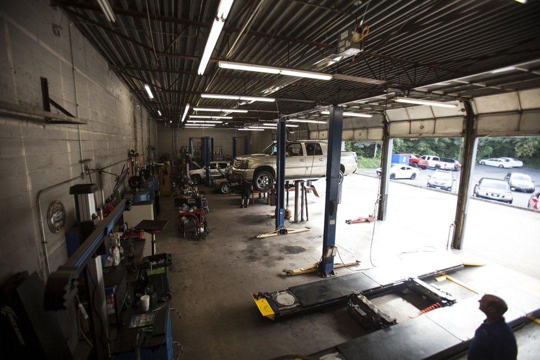 Auto repair shop interior with lifted vehicle, equipment, and open bay facing a parking lot