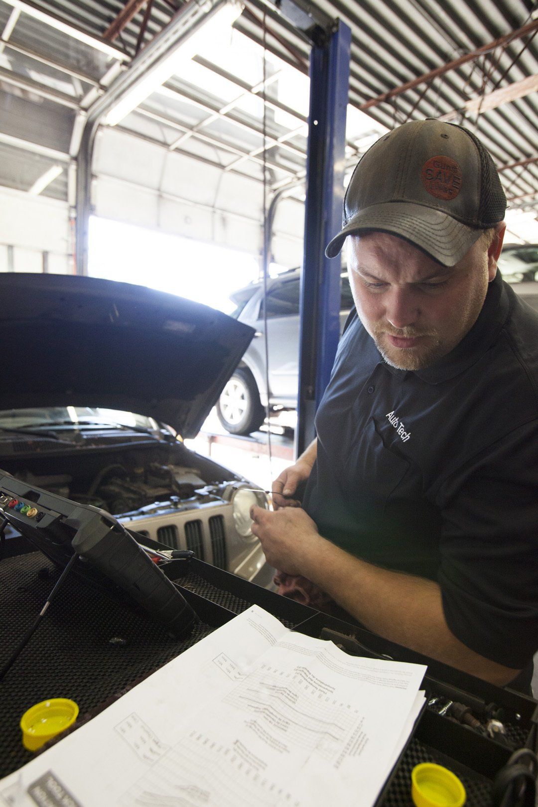 Mechanic working on a car engine in a garage with the hood open