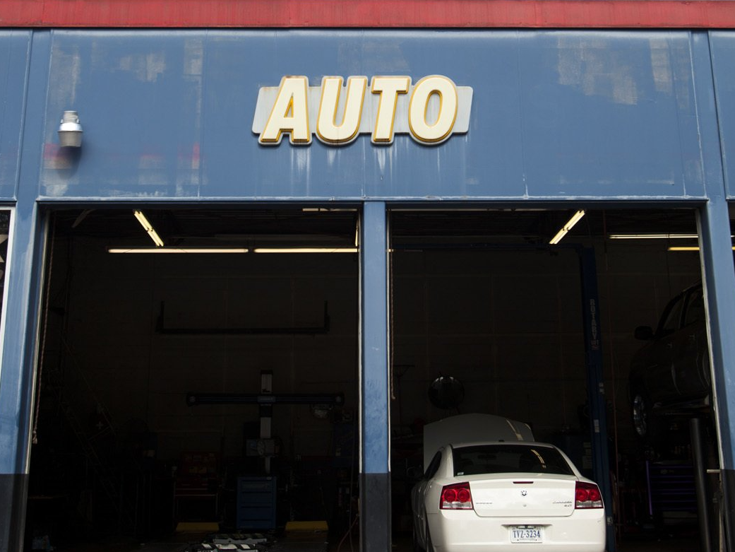 Auto repair garage with blue facade and a white car inside the open bay.