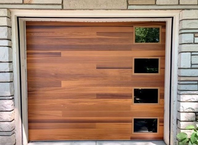 Wood garage door with rectangular windows, set in a stone frame.