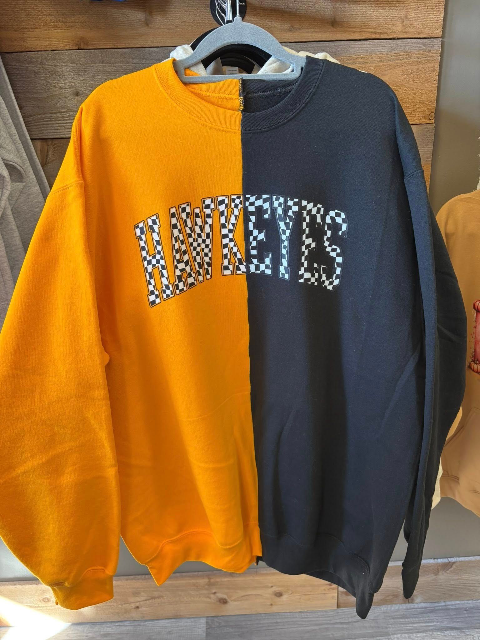 A split-color sweatshirt, half gold and half black, featuring the word 