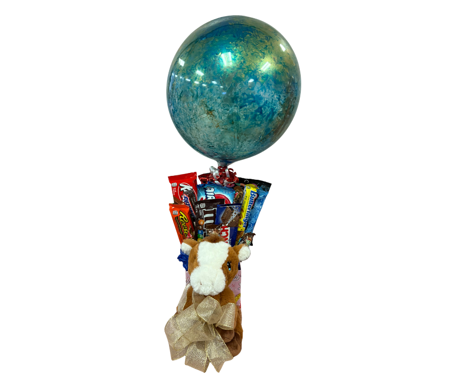 A gift bouquet featuring a blue glittery balloon, a plush cow, and an assortment of candy bars tied with a gold ribbon.