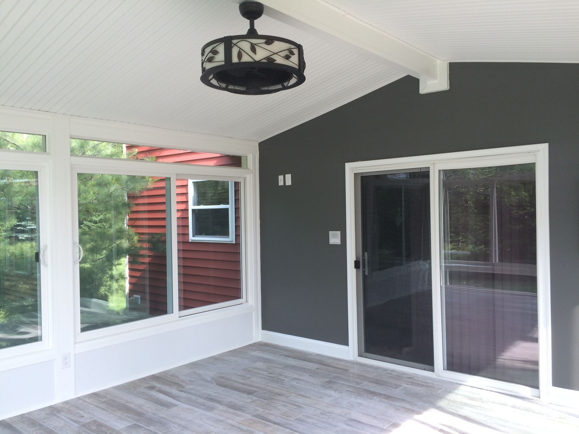 Covered patio with gray walls, white trim, sliding glass doors, and light wood-look flooring
