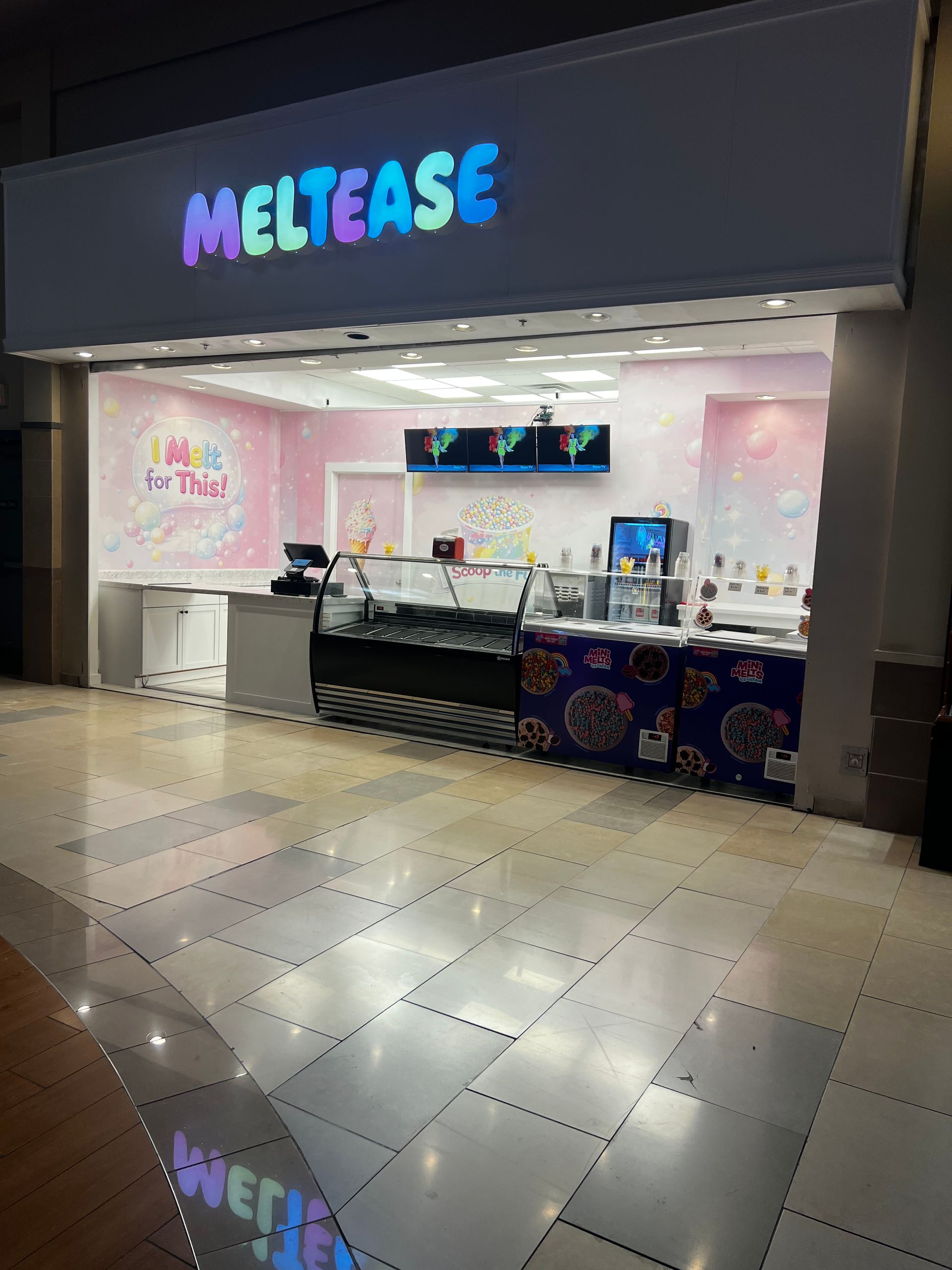 MeltEase dessert kiosk in a mall, with a pink-lit counter and colorful neon sign.