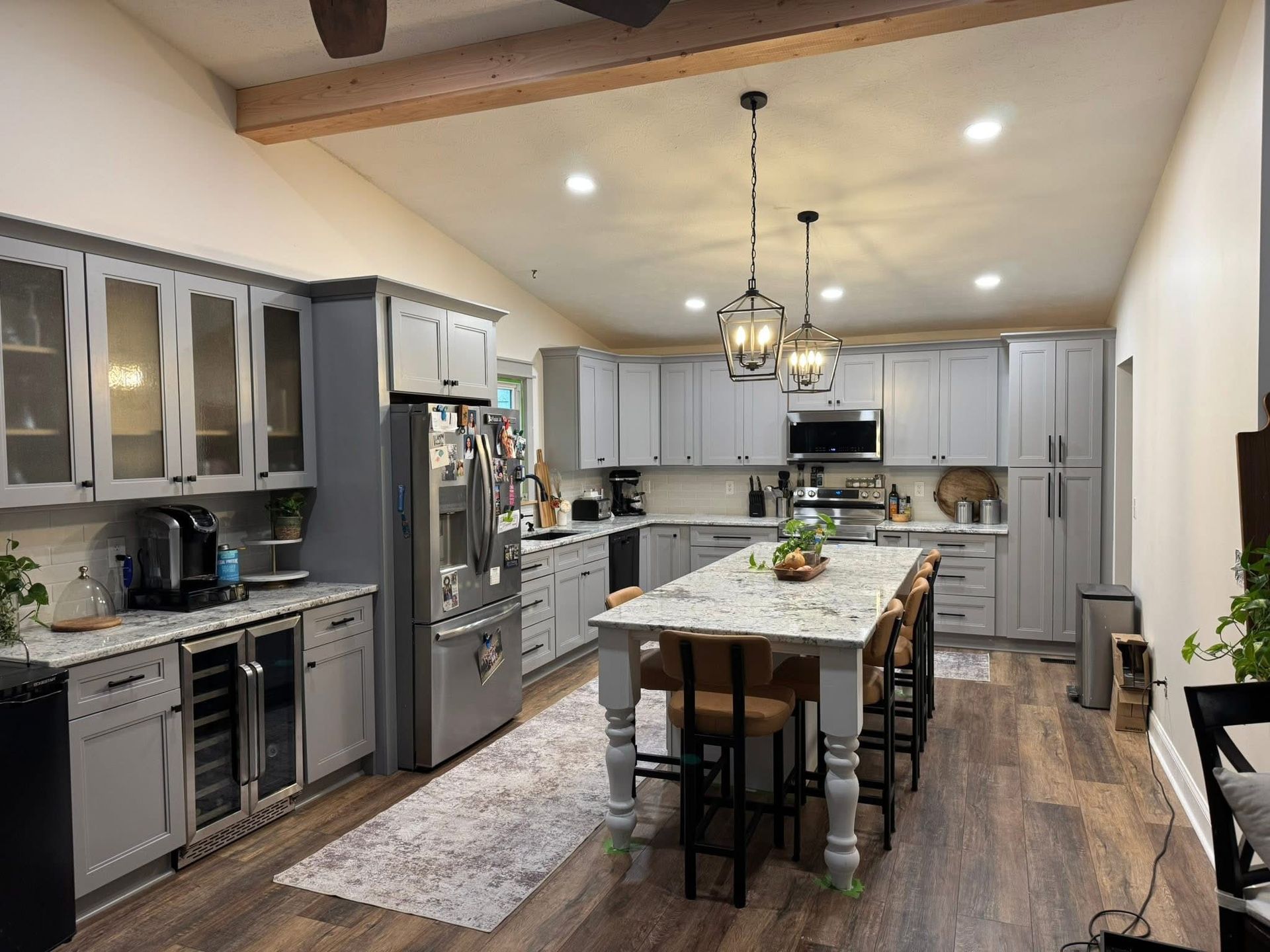 Modern kitchen with gray cabinets, large island, pendant lights, and wood flooring