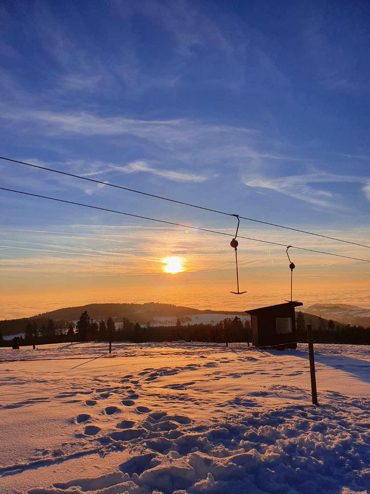 Ein schneebedecktes Feld mit einem Sonnenuntergang im Hintergrund