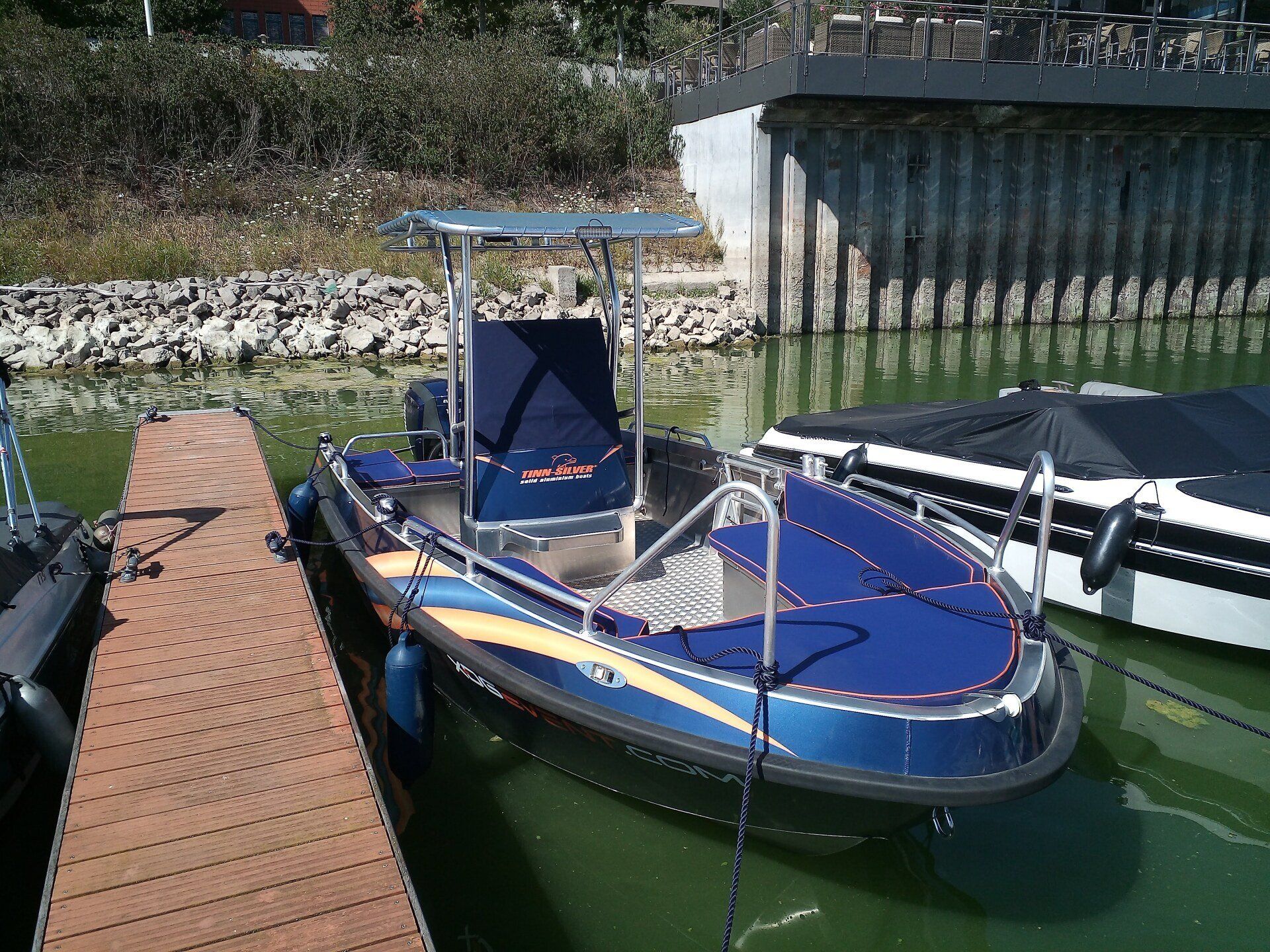 Ein blaues Boot liegt neben einem Holzsteg