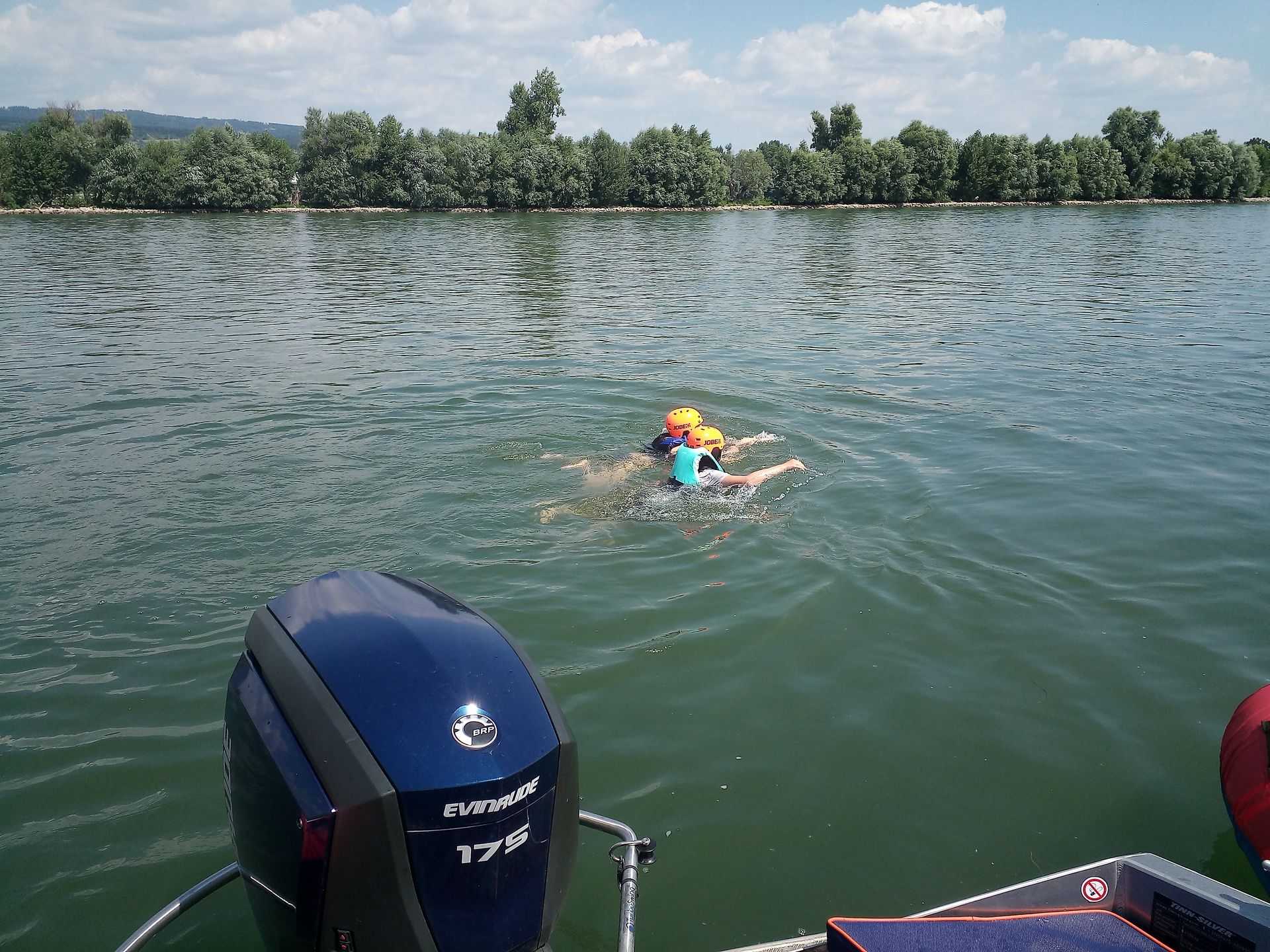 Eine Person schwimmt in einem See neben einem blauen Motor