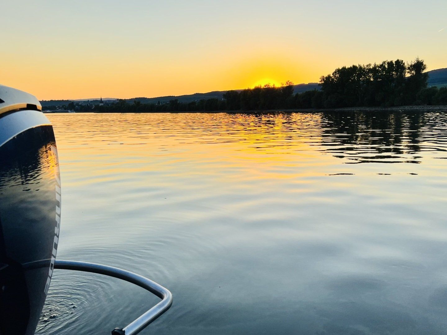 Ein Sonnenuntergang über einem Gewässer mit einem Boot im Vordergrund