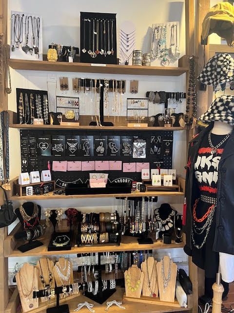 A retail store display featuring multiple wooden shelves filled with various necklaces, bracelets, earrings, and jewelry.