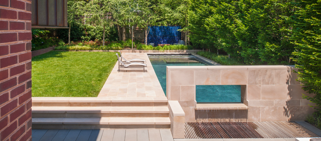 A large swimming pool with stairs and a hot tub in the middle.