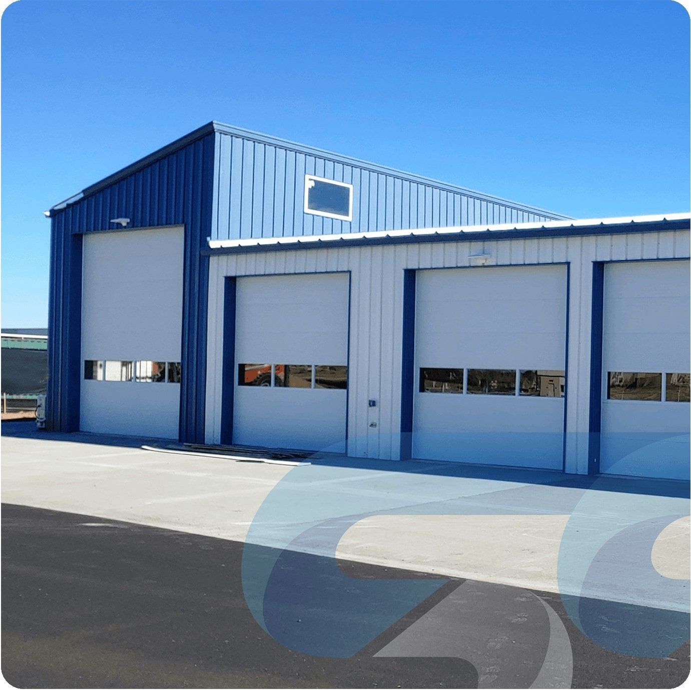 Blue and white industrial building with several closed garage doors.
