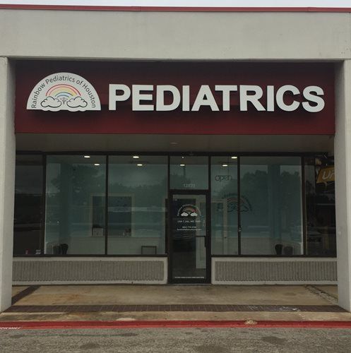 Pediatrics clinic storefront with red sign and glass entrance in a strip mall.
