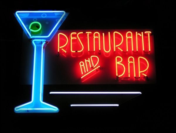 Neon sign for a restaurant and bar, with a blue martini glass and red text on a black background.