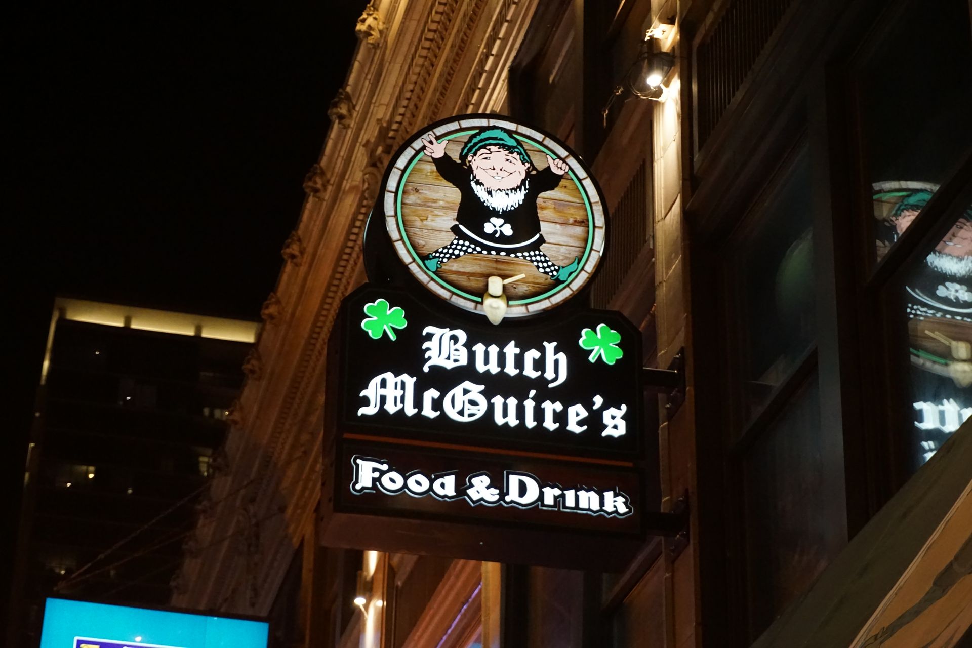 Butch McGuire's bar sign with leprechaun graphic at night.