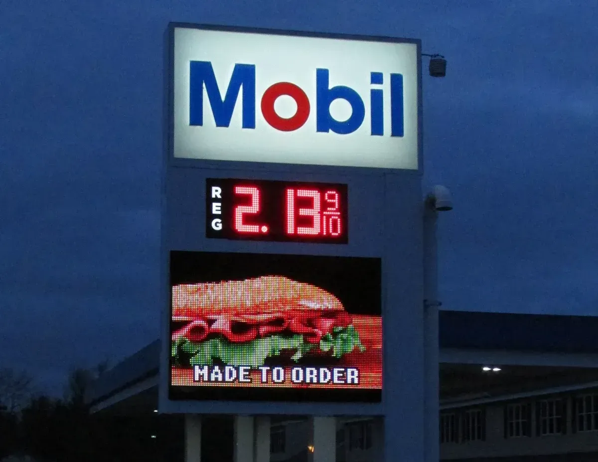 Mobil gas station sign at dusk, showing $2.13/gallon for regular gas and a 