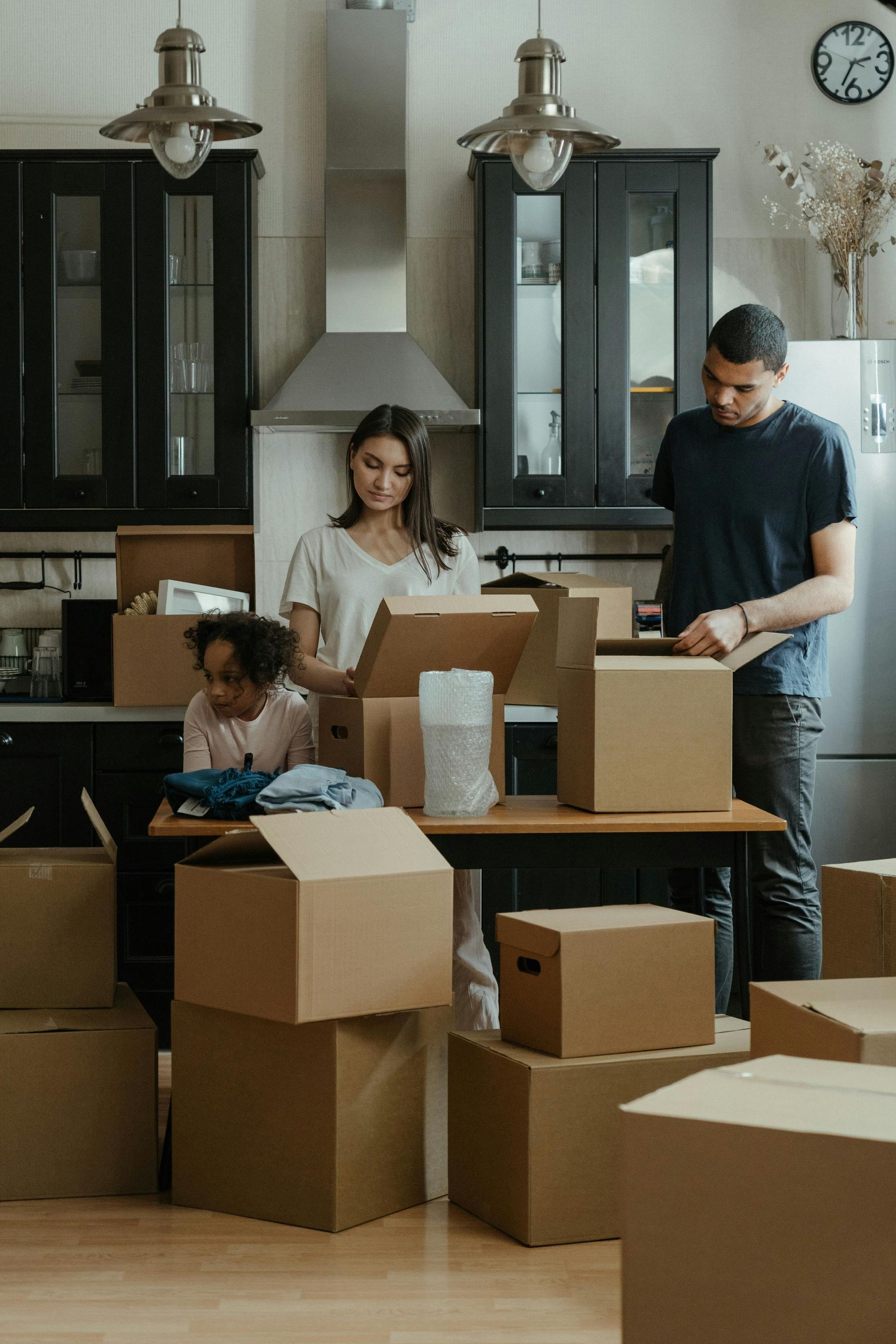 Family unpacking moving boxes in kitchen after relocating to new home