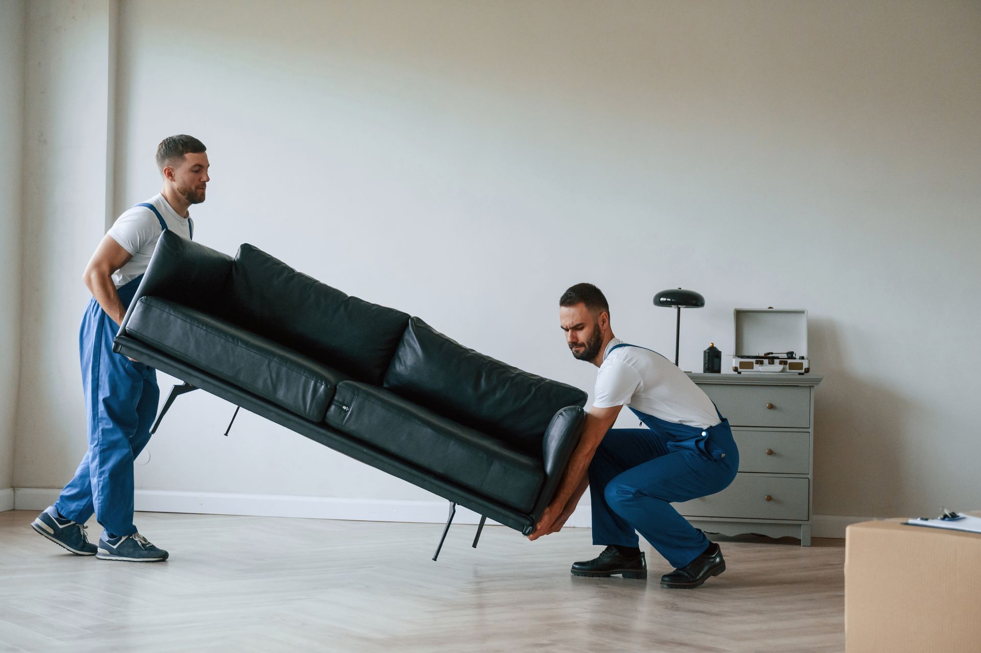 Professional movers carrying a black sofa