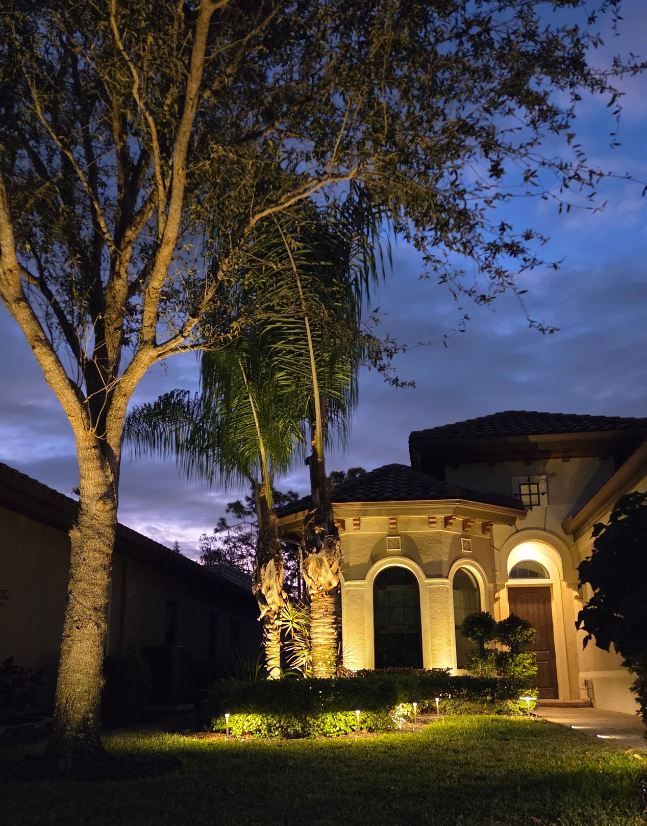 Image of a residential home with architectural lights shining from it at night