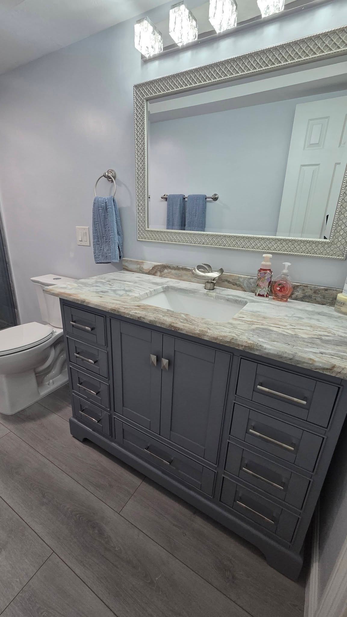 Image of a recent bathroom remodel project. Walls are completely white with a giant mirror