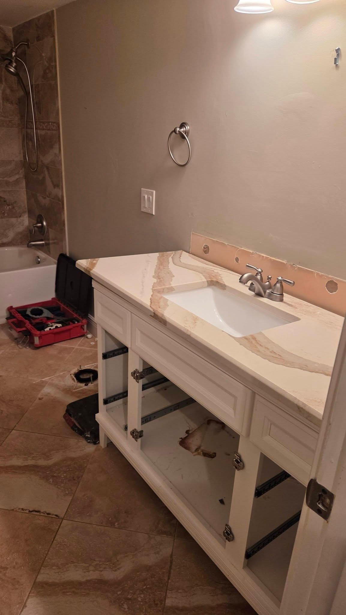 Image of a residential bathroom before a remodel project. Walls are tan and off white with a shower on the left 