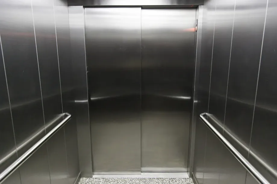 Interno vuoto di un ascensore in acciaio inossidabile con pareti e corrimano a specchio.