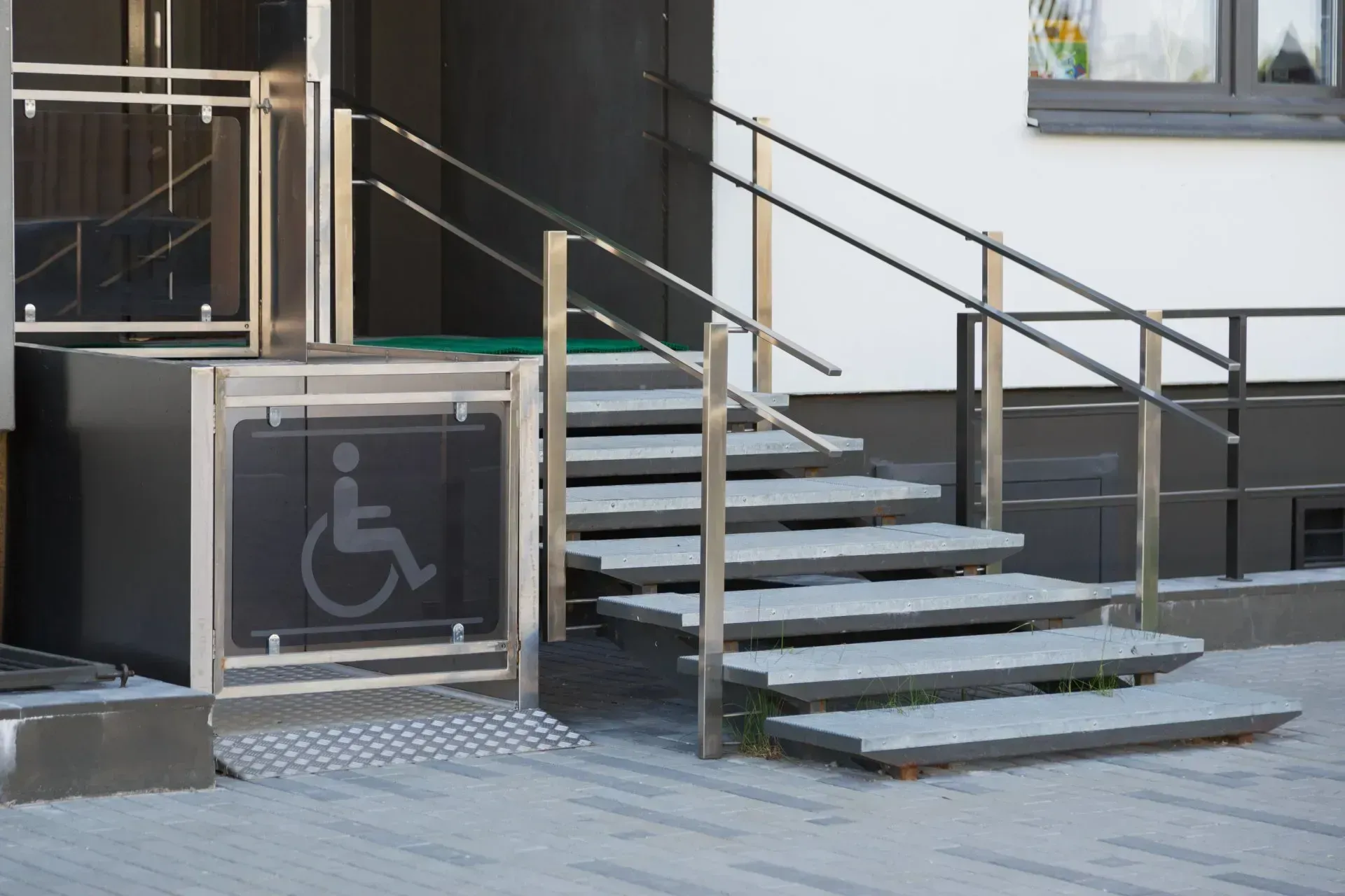 Ingresso dell'edificio accessibile tramite scale e rampa, comprensivo di piattaforma elevatrice per sedie a rotelle.