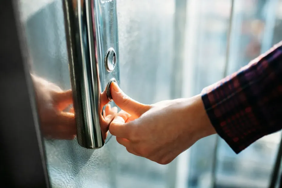 Una mano che apre una porta a vetri con maniglia in metallo e manica a quadri in vista.