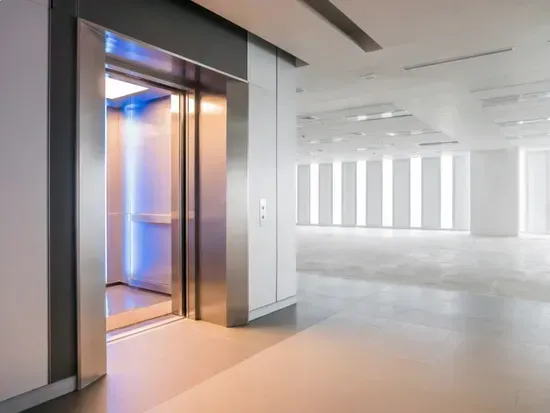 Moderna hall per uffici con ascensore a vista e corridoio luminoso e bianco.