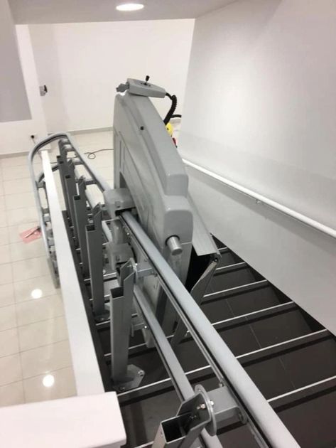 Montascale per interni per sedie a rotelle con gradini neri su pianerottolo bianco.