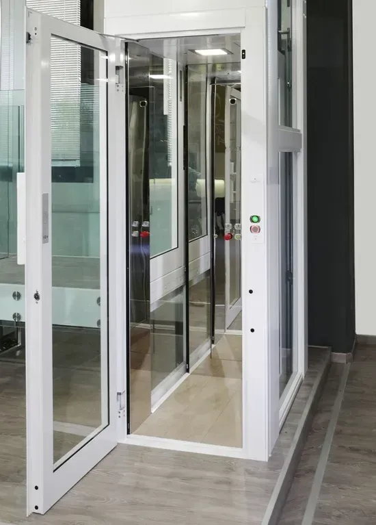 Porte d'ingresso in vetro che conducono alla hall di un edificio moderno, con infissi bianchi e pavimento in legno.