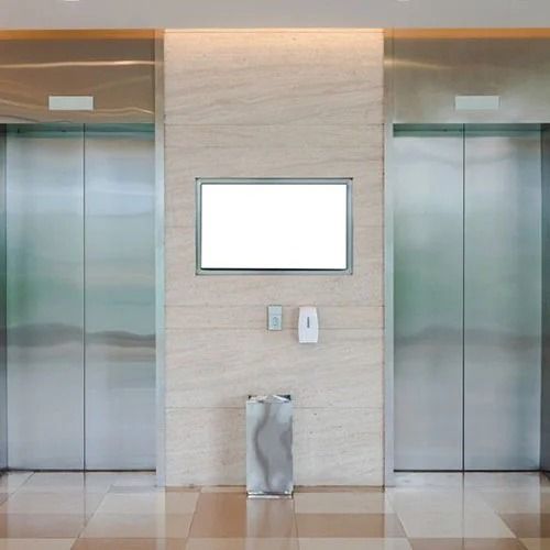 Atrio ascensore moderno con due porte in acciaio inox e pannello espositivo centrale a parete.