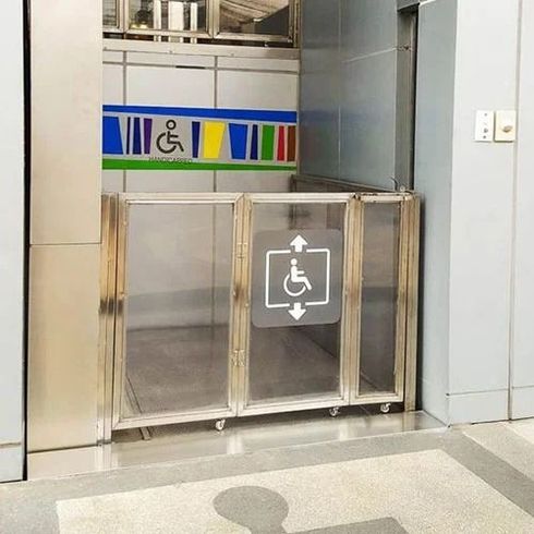 Cancello per bagno accessibile con simbolo di sedia a rotelle su una barriera argentata e striscia di muro colorata alle sue spalle.