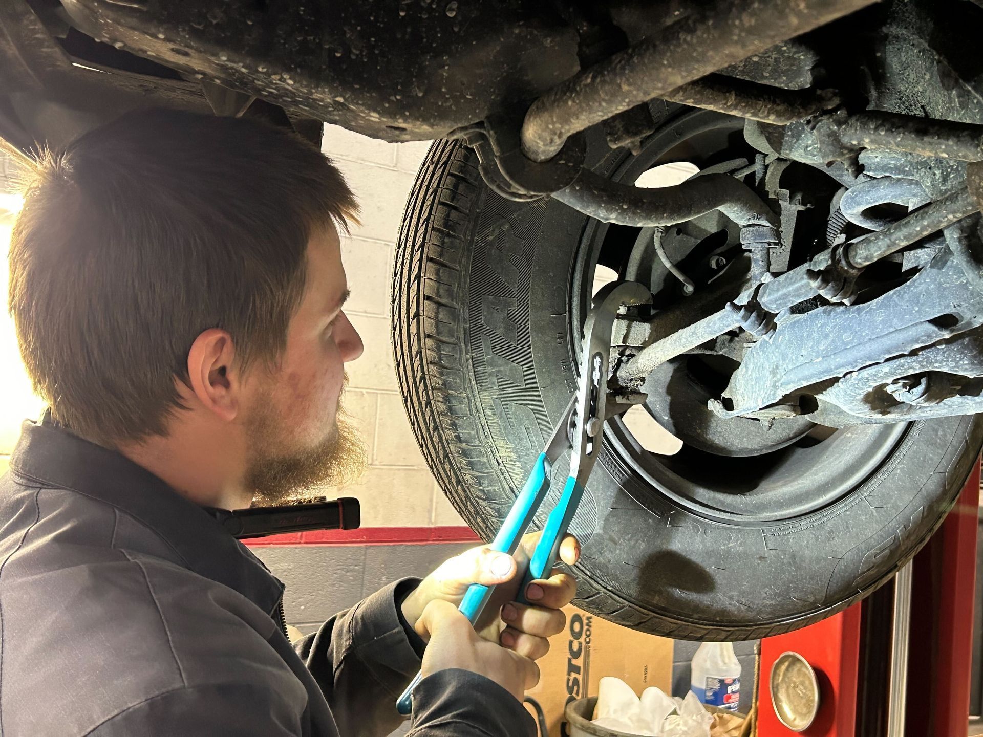 Mechanic Inspecting Suspension Components On Vehicle Lift | Auto DR