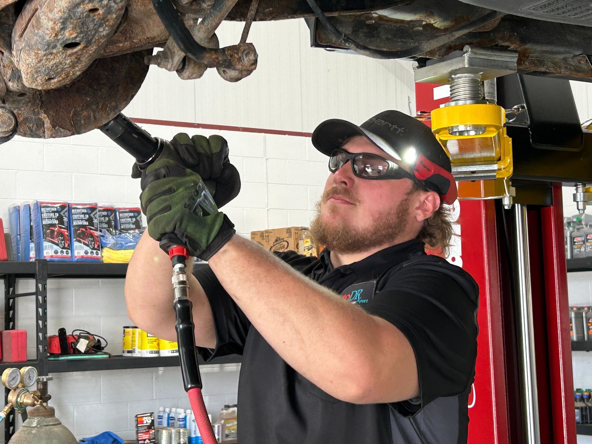 Automotive Technician Performing Undercar Repair On Vehicle Lift | Auto DR